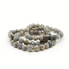 A richly textured sterling silver centerpiece accentuates a handcrafted stretch bracelet with semi-precious Labrodite beads